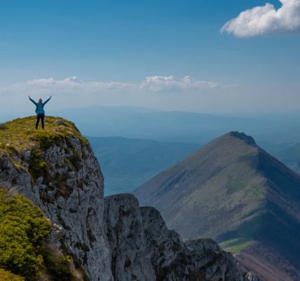 A person celebrating victory atop a mountain peak in Serbia with breathtaking views.