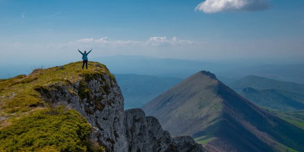 A person celebrating victory atop a mountain peak in Serbia with breathtaking views.